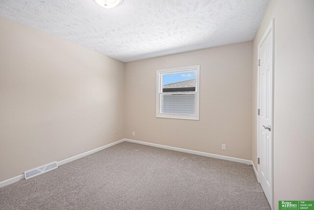 carpeted empty room featuring a textured ceiling, baseboards, and visible vents