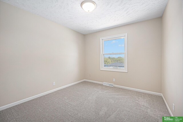 empty room featuring visible vents, carpet, baseboards, and a textured ceiling