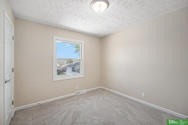 spare room featuring carpet floors, a textured ceiling, baseboards, and visible vents