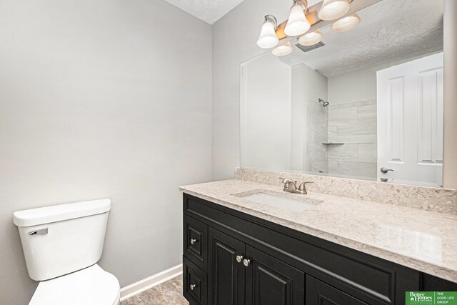 bathroom featuring vanity, toilet, tiled shower, a textured ceiling, and a notable chandelier