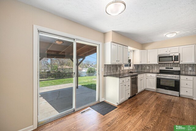 kitchen featuring a sink, dark wood-style flooring, appliances with stainless steel finishes, and backsplash