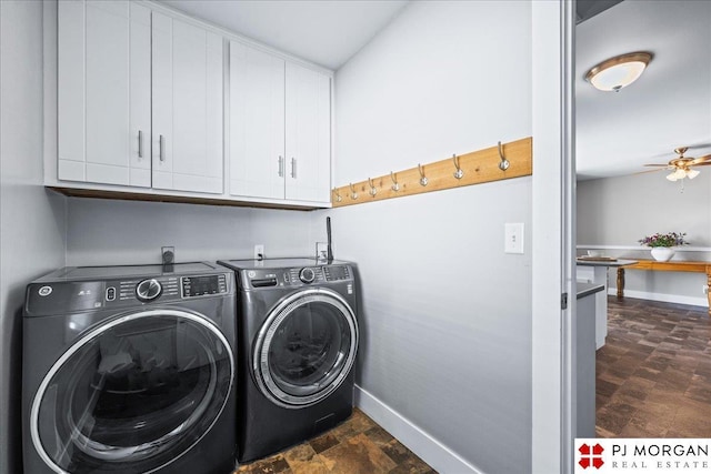 washroom with baseboards, stone finish floor, washer and clothes dryer, a ceiling fan, and cabinet space