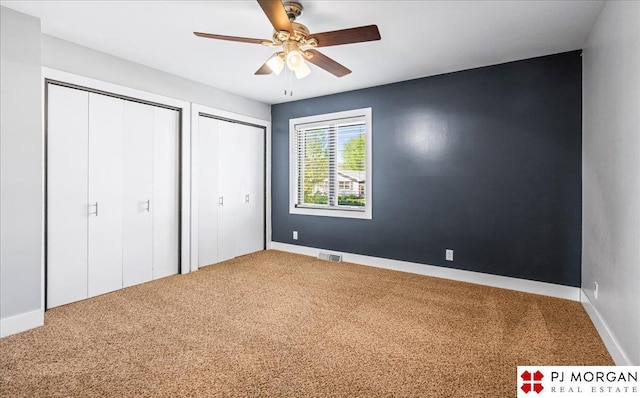 unfurnished bedroom with visible vents, multiple closets, carpet floors, and baseboards