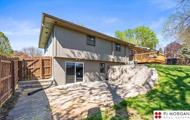 back of property featuring a lawn, fence, and a wooden deck