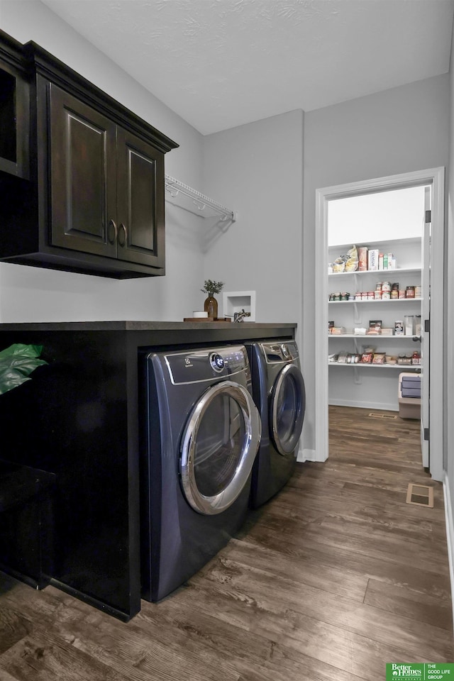 laundry room featuring separate washer and dryer, cabinet space, dark wood-style floors, and visible vents