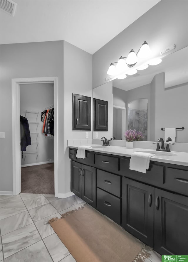 full bath with double vanity, baseboards, a spacious closet, and visible vents