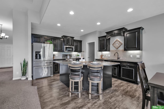 kitchen with backsplash, stainless steel appliances, a sink, and a center island