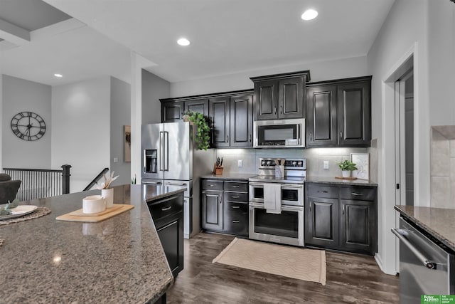 kitchen with dark stone counters, tasteful backsplash, stainless steel appliances, and dark wood-style floors