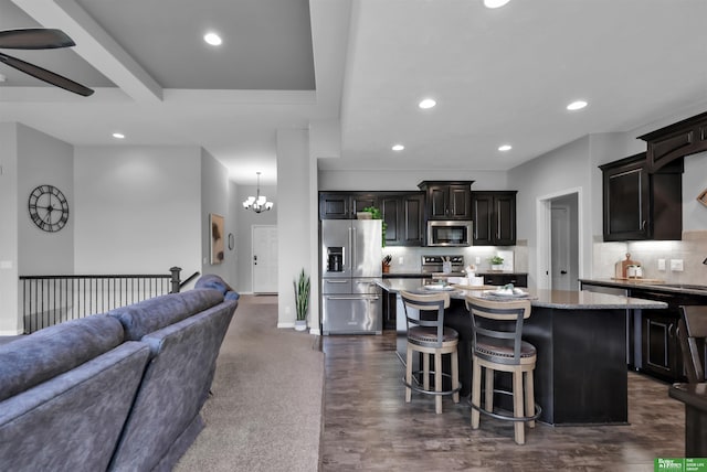 kitchen featuring a kitchen island, open floor plan, a breakfast bar area, tasteful backsplash, and appliances with stainless steel finishes