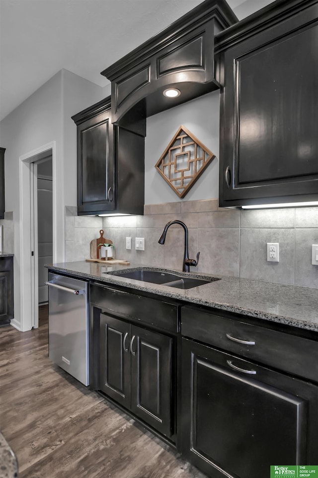 kitchen featuring stone counters, stainless steel dishwasher, a sink, dark wood-style floors, and dark cabinets