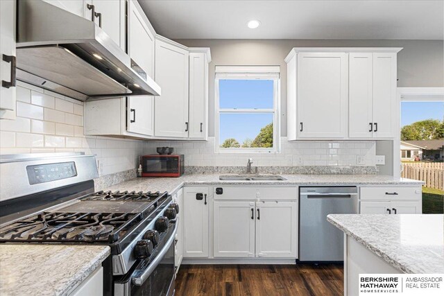8230 Kilpatrick Pkwy, Bennington, NE 68007 - kitchen with stainless steel appliances, wall chimney range hood, a sink, white cabinets, and dark wood-style flooring