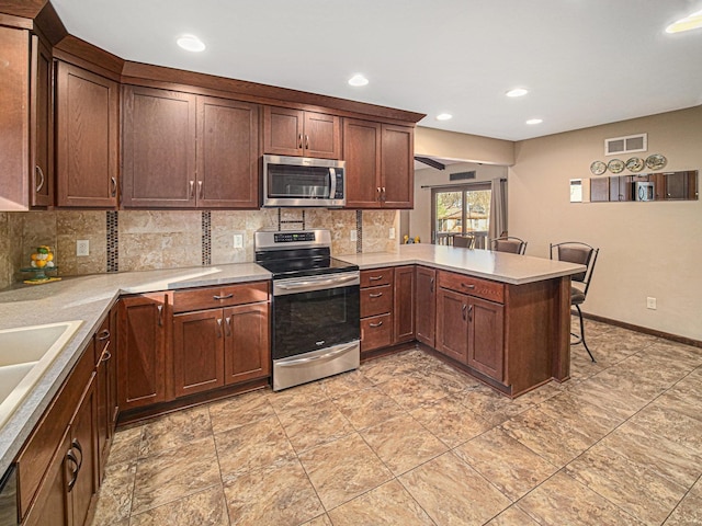 1521 Kingston Rd, Lincoln, NE 68506 - kitchen featuring backsplash, visible vents, light countertops, a peninsula, and stainless steel appliances