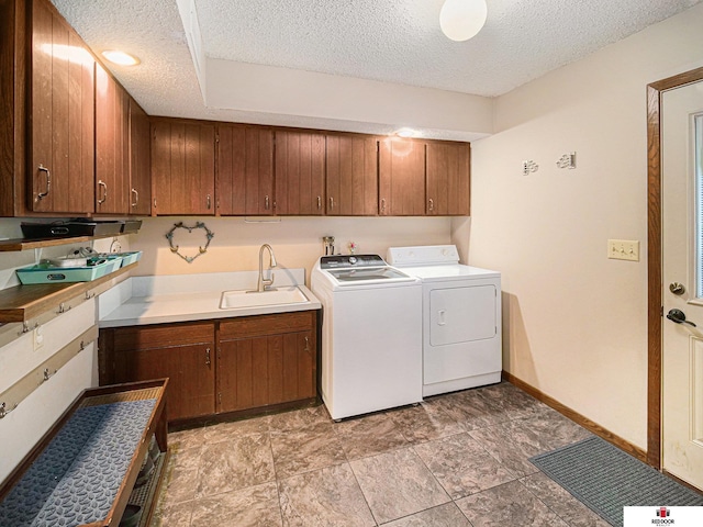 1521 Kingston Rd, Lincoln, NE 68506 - clothes washing area featuring baseboards, a textured ceiling, washing machine and clothes dryer, a sink, and cabinet space