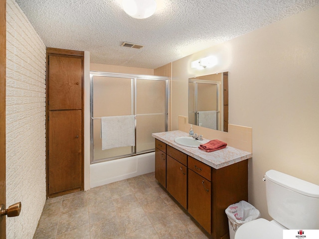 1521 Kingston Rd, Lincoln, NE 68506 - bathroom with shower / bath combination with glass door, vanity, toilet, a textured ceiling, and visible vents
