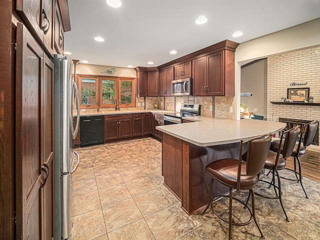 1521 Kingston Rd, Lincoln, NE 68506 - kitchen featuring a breakfast bar, a sink, light countertops, stainless steel appliances, and a peninsula