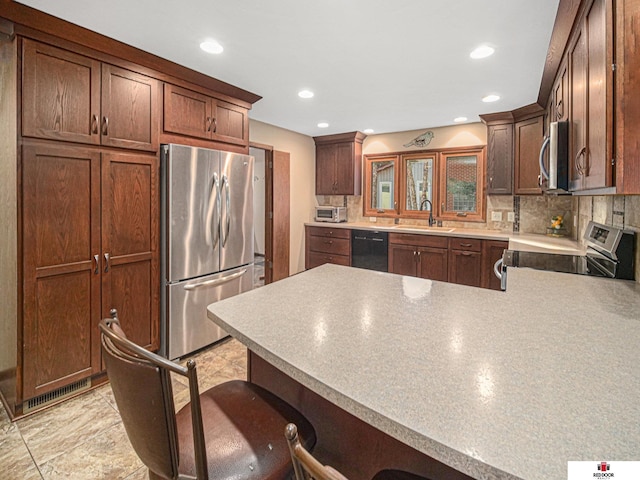 1521 Kingston Rd, Lincoln, NE 68506 - kitchen featuring a breakfast bar area, a peninsula, appliances with stainless steel finishes, and tasteful backsplash