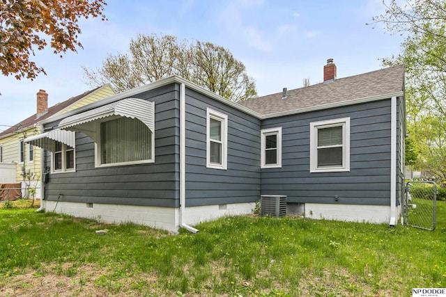view of property exterior with a lawn, central air condition unit, a chimney, and fence
