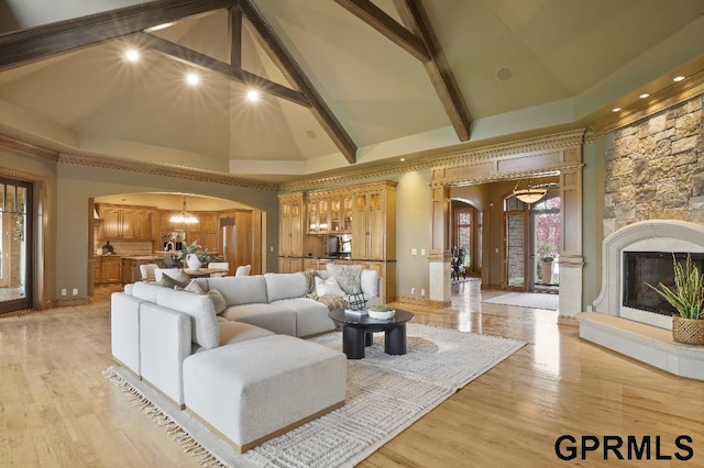 living room featuring light wood-type flooring, arched walkways, a notable chandelier, and high vaulted ceiling