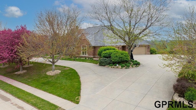 view of front of home featuring brick siding, an attached garage, and curved driveway