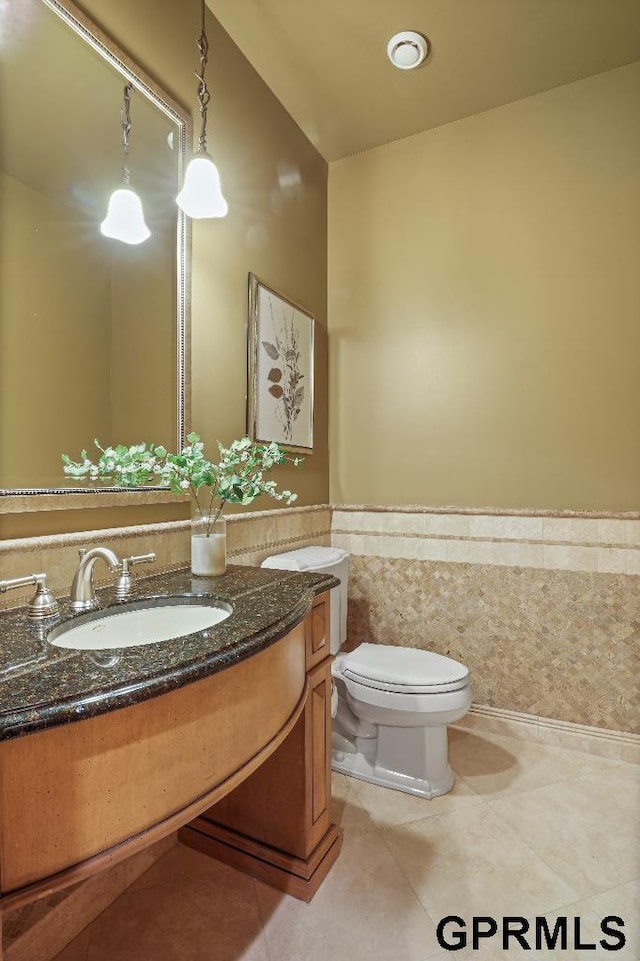 bathroom featuring tile walls, wainscoting, vanity, tile patterned floors, and toilet