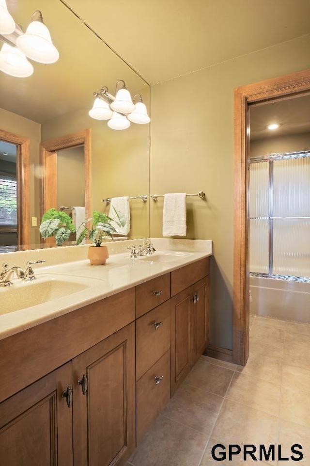 bathroom featuring a sink, tile patterned floors, bath / shower combo with glass door, and double vanity