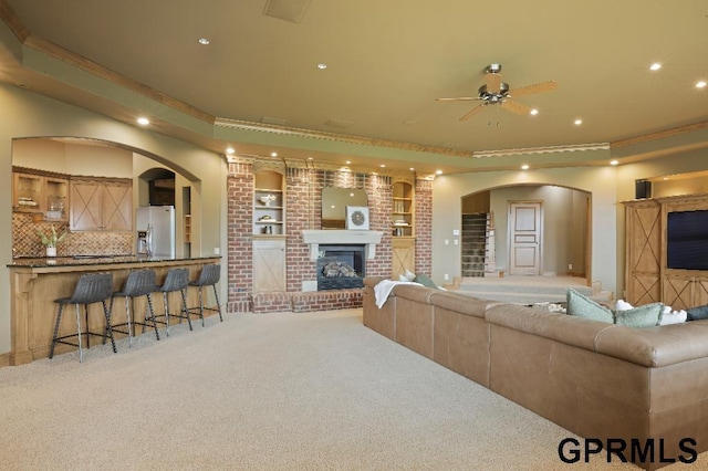 living room with carpet flooring, a brick fireplace, arched walkways, recessed lighting, and a ceiling fan