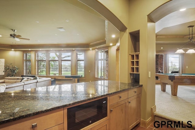 kitchen featuring crown molding, black microwave, plenty of natural light, billiards, and dark stone countertops