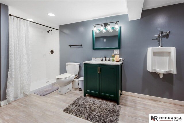 bathroom with a tile shower, vanity, toilet, baseboards, and wood finished floors