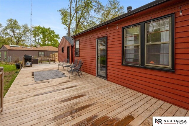 wooden terrace featuring outdoor dining area, fence, and area for grilling