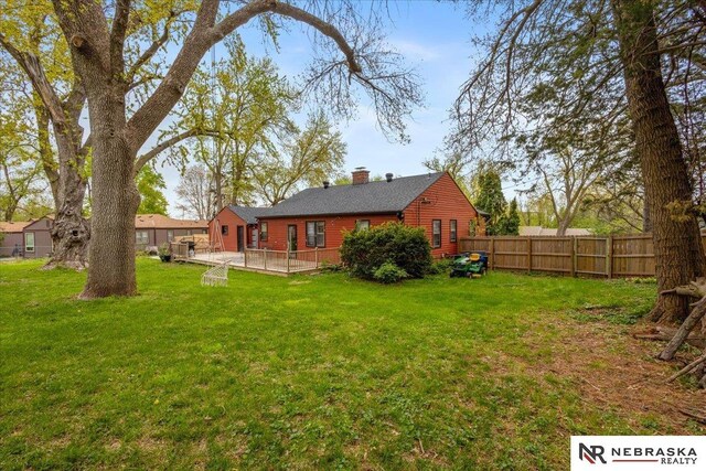 rear view of house with fence, a chimney, a yard, and a deck