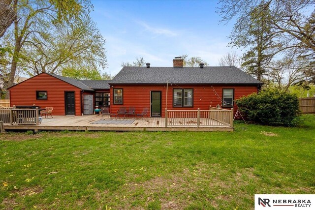 rear view of house with a lawn, fence, a chimney, and a deck