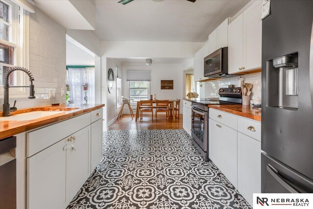 kitchen with a sink, appliances with stainless steel finishes, wooden counters, and tasteful backsplash