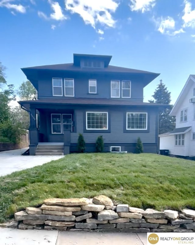 rear view of property featuring a lawn and covered porch