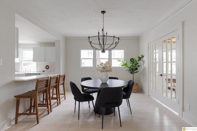 dining area with crown molding, a chandelier, a wealth of natural light, and light wood-type flooring