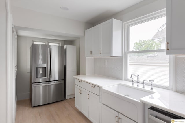 kitchen featuring appliances with stainless steel finishes, a sink, light countertops, white cabinets, and light wood-style flooring