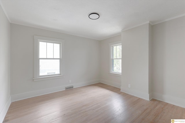 unfurnished room with visible vents, ornamental molding, light wood-style flooring, and baseboards