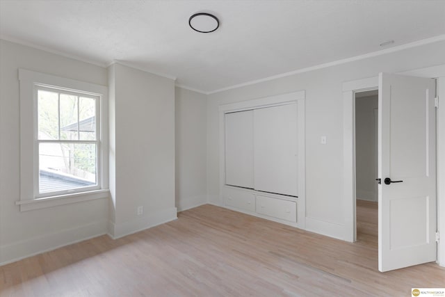 unfurnished bedroom with crown molding, a closet, baseboards, and light wood-type flooring