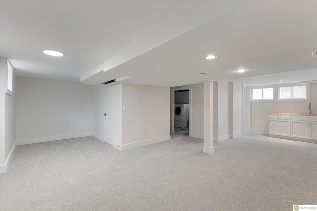 basement with washer / clothes dryer, a sink, baseboards, light carpet, and recessed lighting
