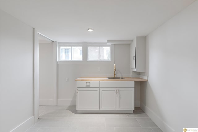 bar with baseboards, a sink, light tile patterned floors, and recessed lighting