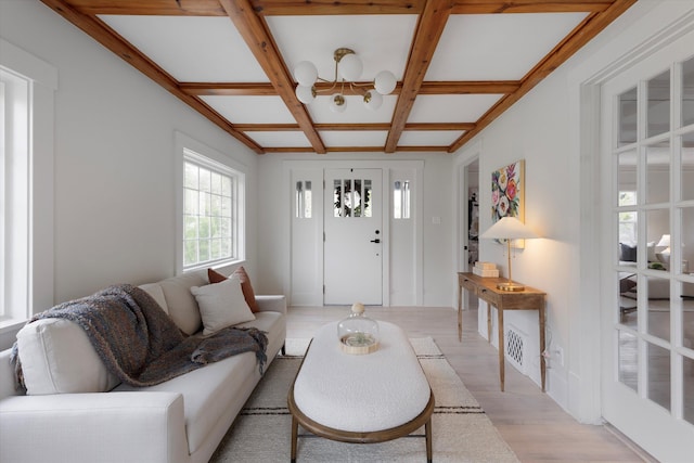 living room featuring light wood-type flooring, coffered ceiling, a notable chandelier, and beamed ceiling