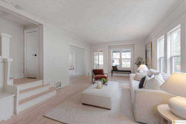 living area with visible vents, ornamental molding, light wood-style flooring, and stairs