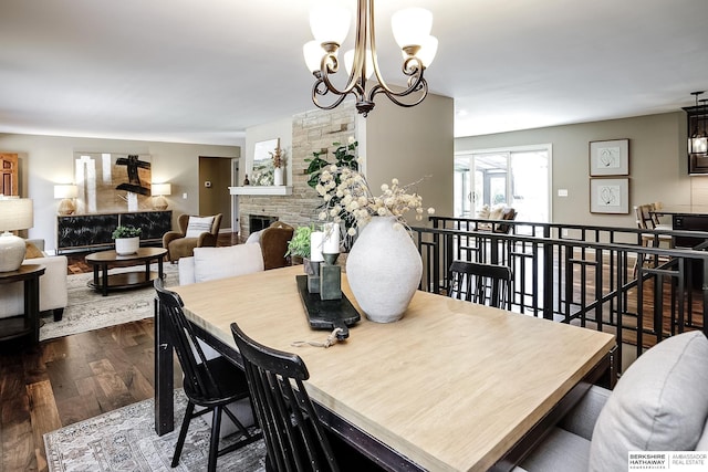 dining room with a fireplace, a notable chandelier, and dark wood finished floors