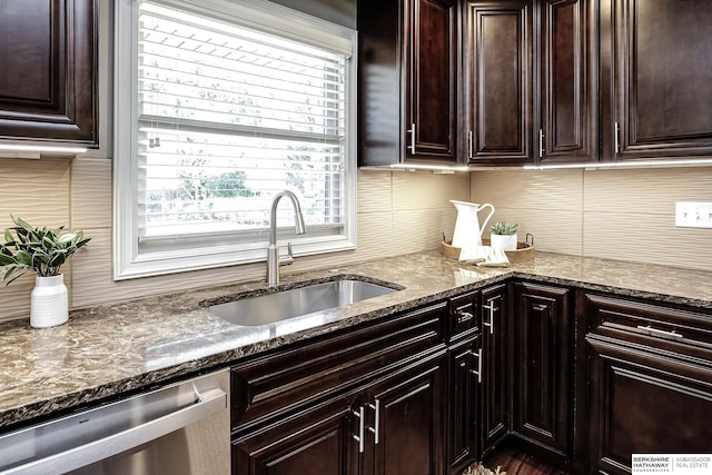 kitchen with dark stone counters, dishwasher, backsplash, and a sink