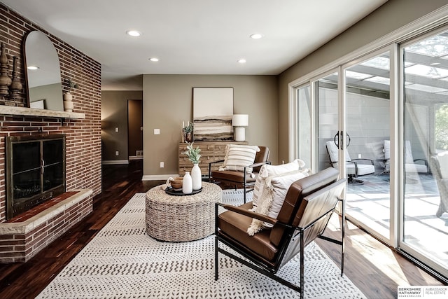 living room featuring baseboards, hardwood / wood-style floors, recessed lighting, and a brick fireplace