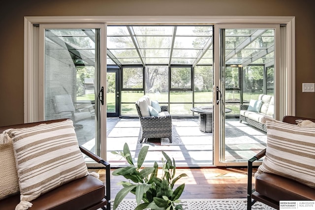doorway with a sunroom, wood finished floors, and a healthy amount of sunlight