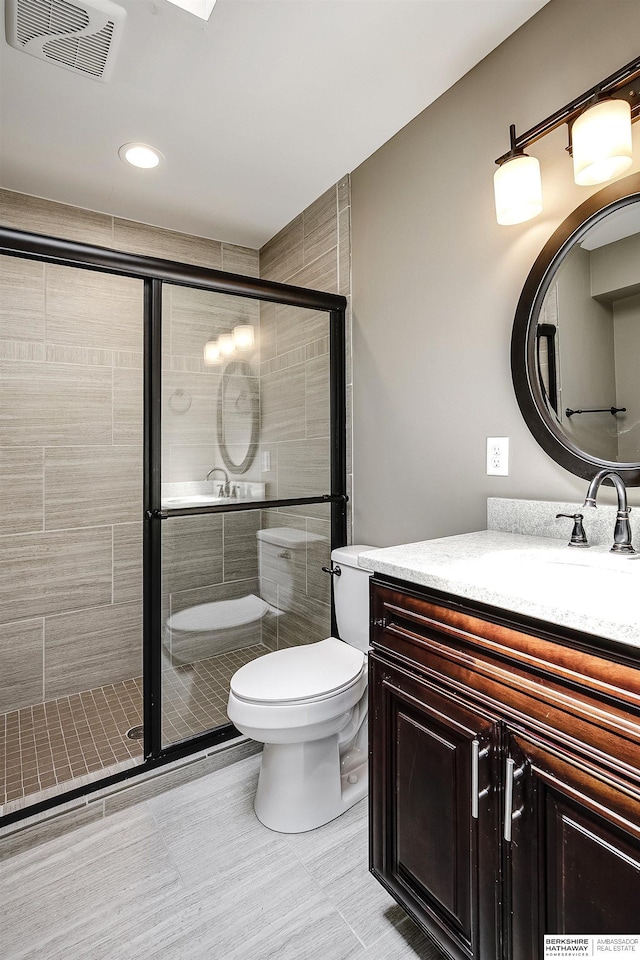 bathroom featuring toilet, a stall shower, visible vents, tile patterned flooring, and vanity