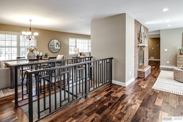 hall with an upstairs landing, a chandelier, baseboards, wood finished floors, and recessed lighting