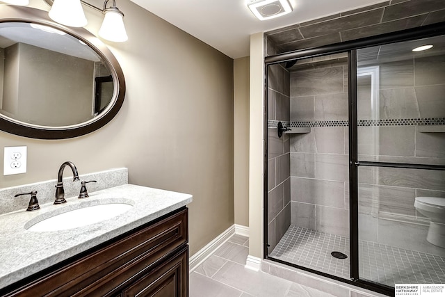 bathroom featuring baseboards, marble finish floor, toilet, a shower stall, and vanity