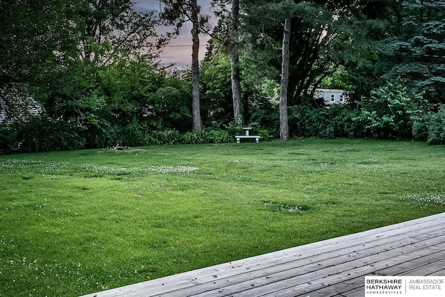 view of grassy yard featuring a wooden deck and view of scattered trees