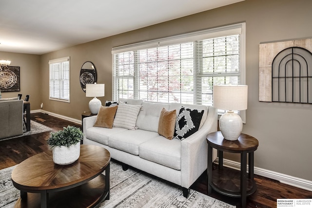 living area with visible vents, baseboards, a notable chandelier, and wood finished floors